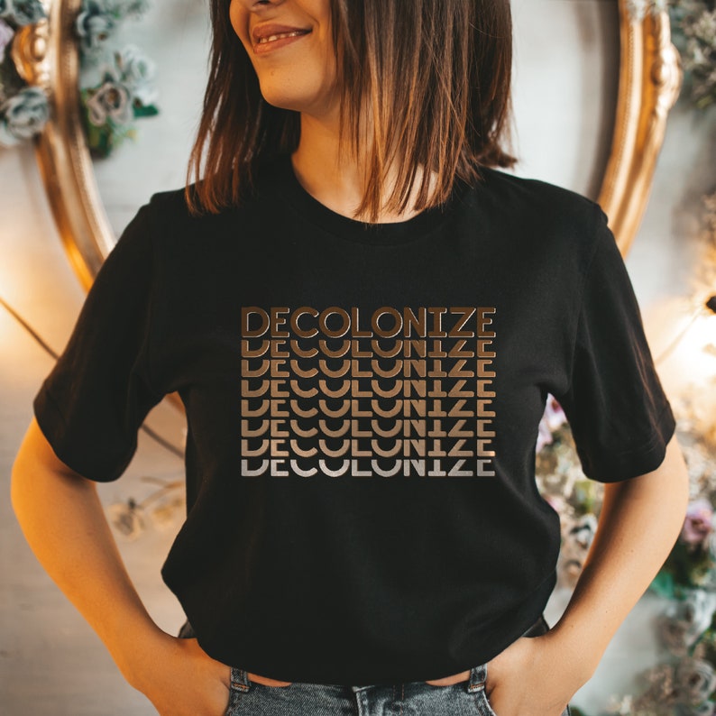May include: A black t-shirt with the text "DECOLONIZE" repeated in a gradient of brown shades.