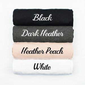 Puede incluir: Cuatro camisetas enrolladas en diferentes colores: negro, gris oscuro jaspeado, melocot&oacute;n jaspeado y blanco. El color de cada camiseta est&aacute; escrito en blanco sobre la tela.