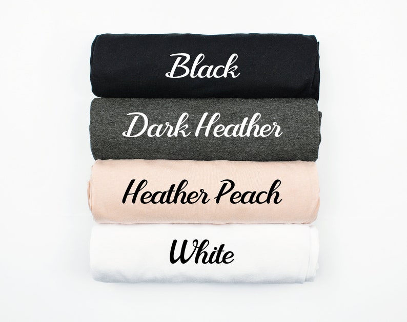 Puede incluir: Cuatro camisetas enrolladas en diferentes colores: negro, gris oscuro jaspeado, melocot&oacute;n jaspeado y blanco. El color de cada camiseta est&aacute; escrito en blanco sobre la tela.