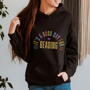 May include: Black hoodie with a rainbow colored graphic that says "It's a good day for beading" with a small heart in the middle of the text.