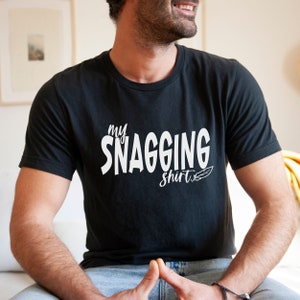 May include: A black t-shirt with white text that says "my snagging shirt" and a small feather design.