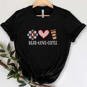 May include: Black t-shirt with a flower, heart, and coffee cup graphic. The text "Bead Love Coffee" is printed below the graphic.