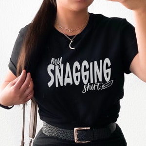 May include: Black t-shirt with the text "my snagging shirt" in silver lettering with a small feather design.