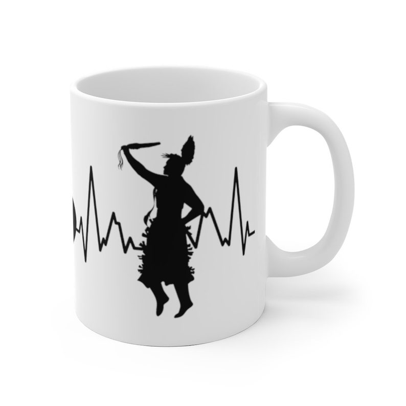 May include: White ceramic mug with a black silhouette of a Native American dancer with a heartbeat line behind them.