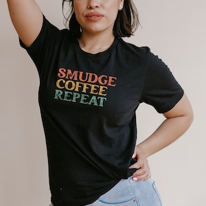 May include: A black t-shirt with the text "SMUDGE COFFEE REPEAT" in a retro font with colorful accents.