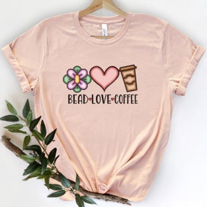 May include: A pink t-shirt with a flower, heart, and coffee cup graphic. The text "Bead Love Coffee" is printed below the graphic.