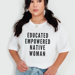 May include: White t-shirt with black text that reads "EDUCATED EMPOWERED NATIVE WOMAN".