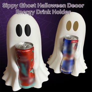 May include: White ghost-shaped Halloween drink holders, each holding a can of soda. One ghost has black eye cutouts, the other has gold. The text "Sippy Ghost Halloween Decor Energy Drink Holder" is at the top. The background is purple with a spiderweb design.