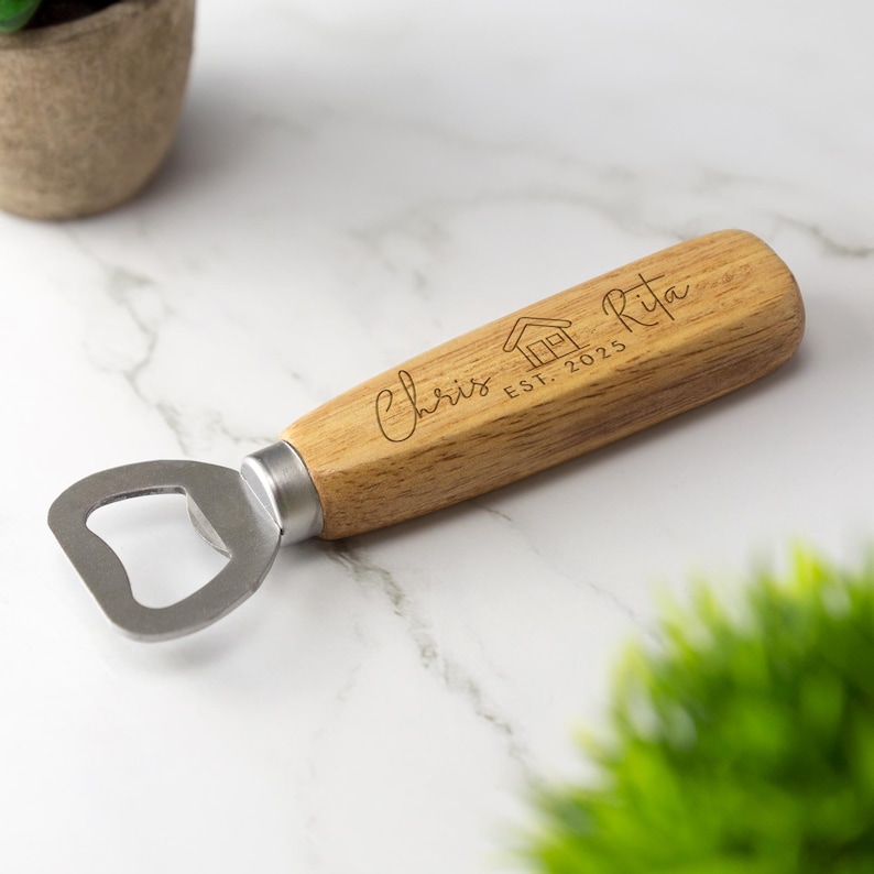 May include: A wooden bottle opener with a metal opener and a handle engraved with "Chris & Rita Est. 2025" and a house icon.
