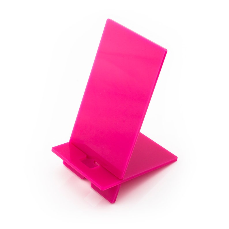 May include: A bright pink plastic phone stand. The stand is designed to hold a phone upright.
