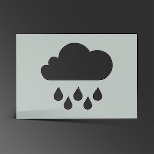 May include: A black cloud and six raindrops cut out of a white rectangular stencil. The stencil is on a dark grey background. The cloud has a rounded shape with a textured appearance, and the raindrops are teardrop-shaped.