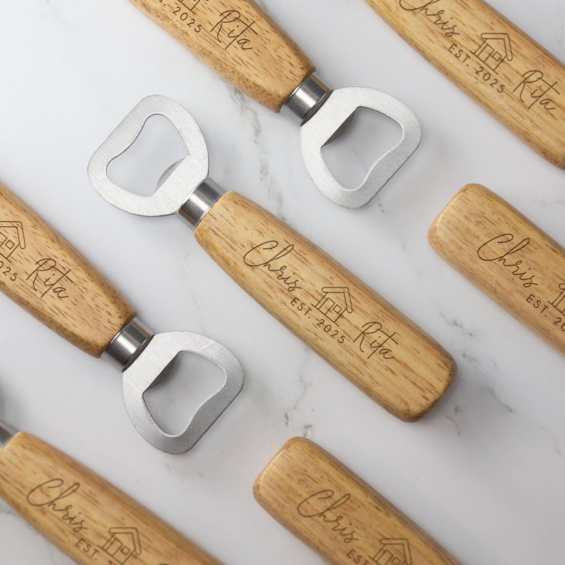 May include: Set of five wooden bottle openers with a personalized engraved design. Each opener features the names "Chris" and "Rita" with the text "EST. 2025" and a small house icon.