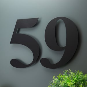 May include: Black metal house number plaque with the number 59 in a stylised font.