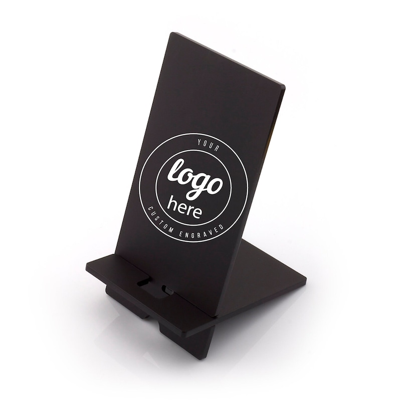 May include: Black phone stand with a circular logo that says "Your logo here Custom Engraved".