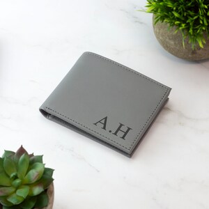 May include: A gray leather wallet with the initials "A.H." embossed on the front.