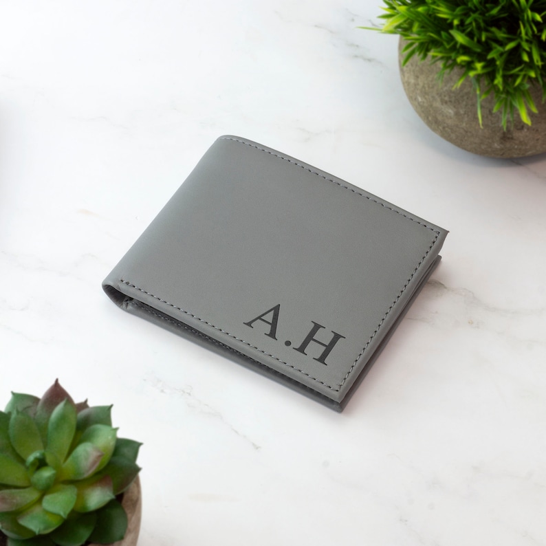 May include: A gray leather wallet with the initials "A.H." embossed on the front.