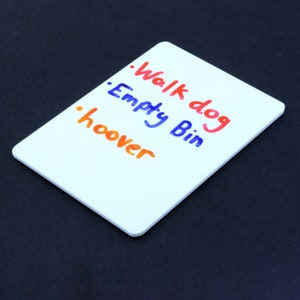 May include: White dry-erase board with three handwritten to-do list items: "Walk dog", "Empty Bin", and "Hoover".