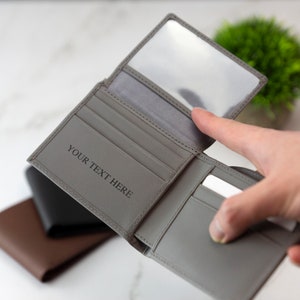 May include: Gray leather wallet with a clear plastic window and multiple card slots. The wallet is open and the text "YOUR TEXT HERE" is visible on the inside.