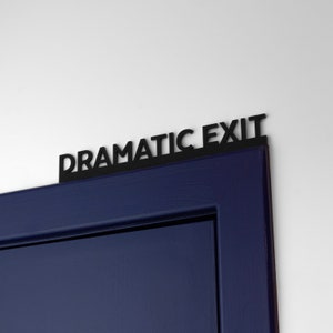 K&ouml;nnte beinhalten: Eine dunkelblaue T&uuml;r mit einem schwarzen Schild, auf dem "Dramatic Exit" steht.