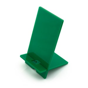 May include: A green plastic phone stand with a raised lip to hold a phone upright.