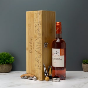 May include: A bamboo wine box with a floral design and the text "Theo & Poppy" engraved on the front. The box includes a bottle of rose wine, a corkscrew, a bottle stopper, and a wine pourer.