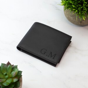 May include: A black leather wallet with the initials "G.M." embossed on the front.
