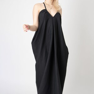 Pode incluir: Um vestido maxi preto com decote em V e al&ccedil;as finas. O vestido tem um caimento solto e fluido e &eacute; feito de um tecido macio e confort&aacute;vel.