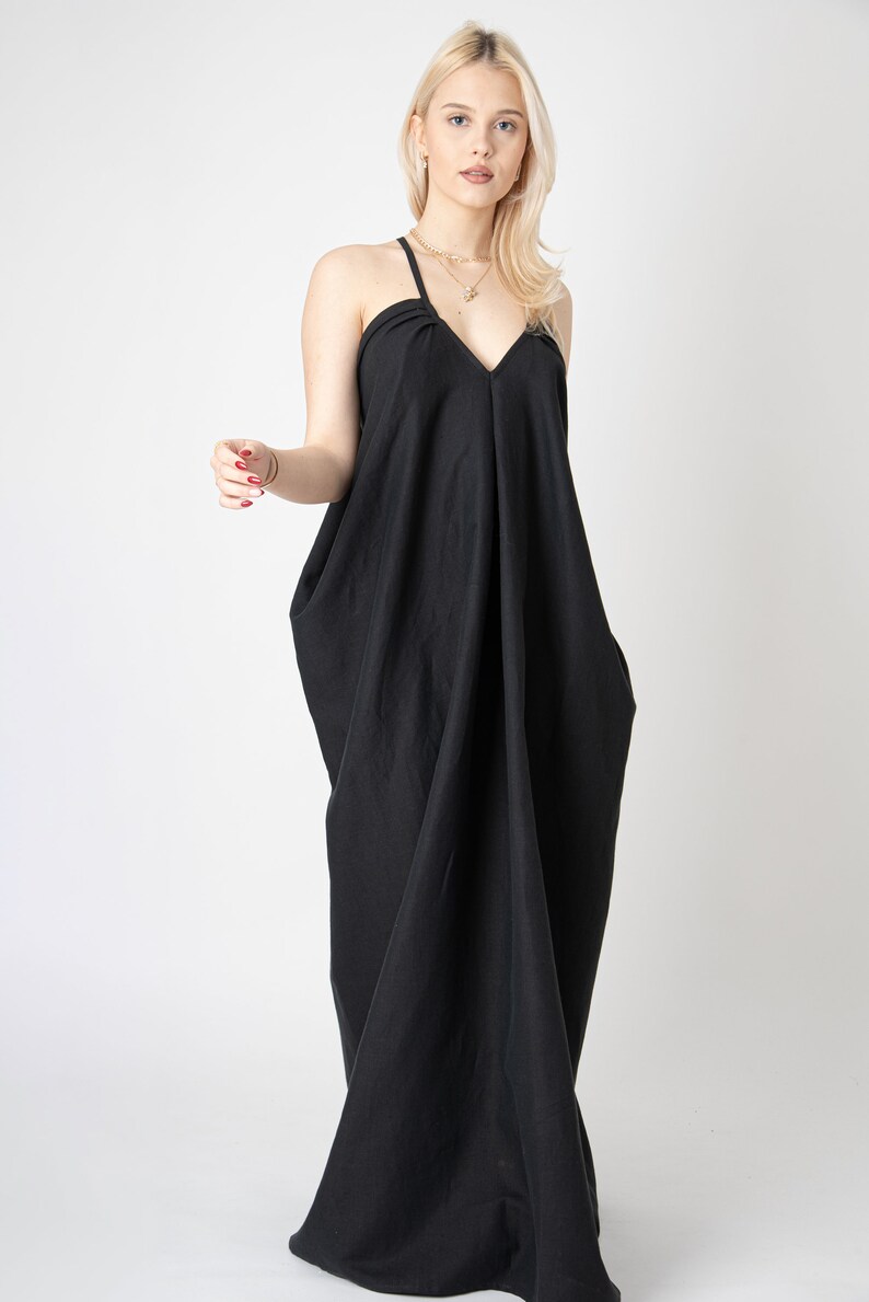 Pode incluir: Um vestido maxi preto com decote em V e al&ccedil;as finas. O vestido tem um caimento solto e fluido e &eacute; feito de um tecido macio e confort&aacute;vel.