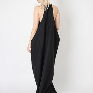 Pode incluir: Um vestido maxi preto sem mangas com um design fluido e drapeado. O vestido &eacute; feito de um tecido leve e tem um caimento solto.