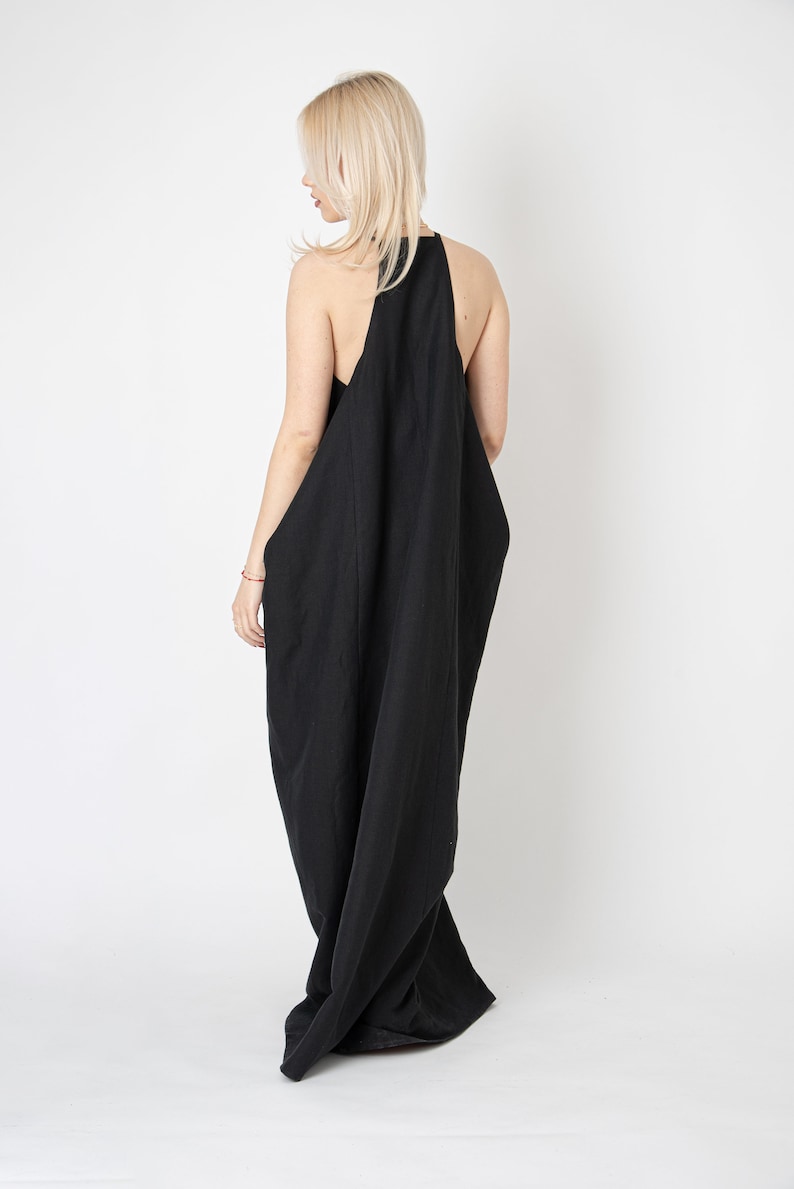 Pode incluir: Um vestido maxi preto sem mangas com um design fluido e drapeado. O vestido &eacute; feito de um tecido leve e tem um caimento solto.