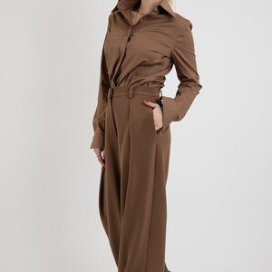 May include: A brown collared shirt with long sleeves and a brown pair of wide-leg pants.