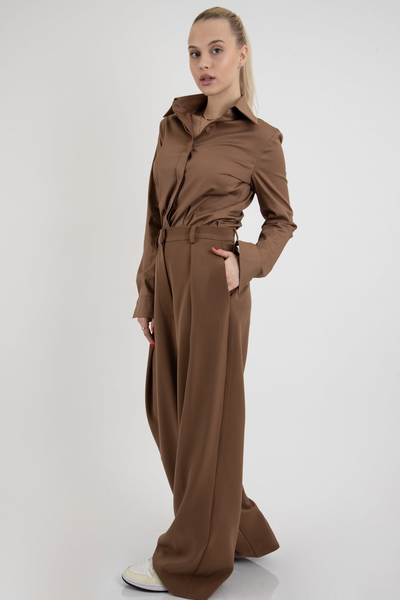 May include: A brown collared shirt with long sleeves and a brown pair of wide-leg pants.