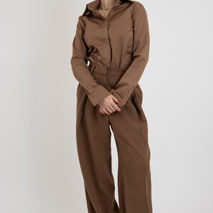 May include: A brown long-sleeved shirt with a collared neckline and a brown pair of wide-leg pants.