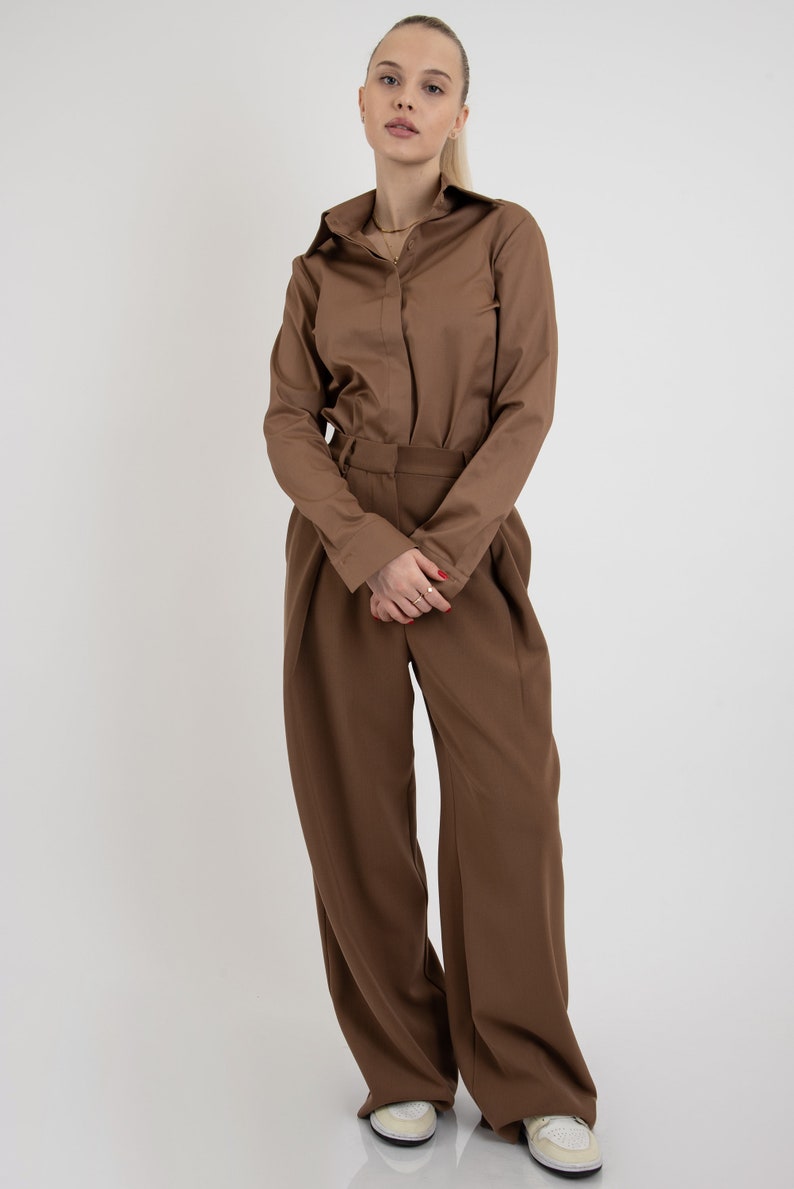 May include: A brown long-sleeved shirt with a collared neckline and a brown pair of wide-leg pants.
