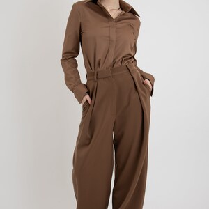 May include: A brown long-sleeved button-down shirt with a matching pair of wide-leg pants. The pants have pleats at the front and pockets on the sides.