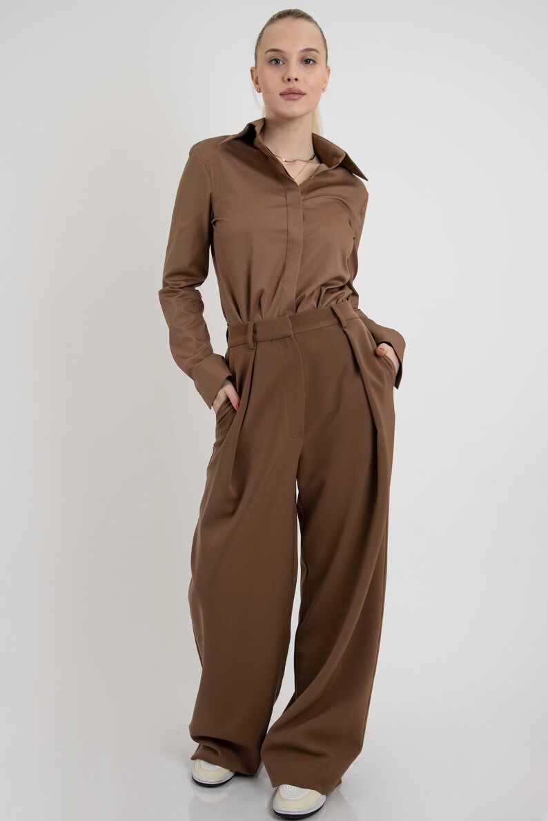 May include: A brown long-sleeved button-down shirt with a matching pair of wide-leg pants. The pants have pleats at the front and pockets on the sides.