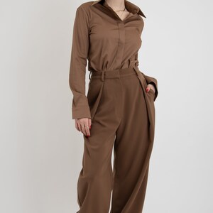 May include: A brown long-sleeved shirt with a collared neckline and a brown pair of wide-leg pants.