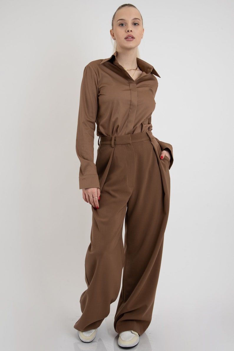 May include: A brown long-sleeved shirt with a collared neckline and a brown pair of wide-leg pants.