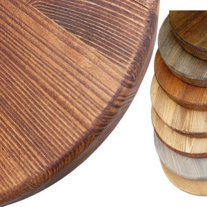May include: A set of round wooden tabletops in various shades of brown, from light to dark. The tabletops are made of natural wood with visible grain patterns.