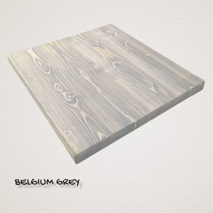 May include: A rectangular wooden tabletop in a light grey colour with a wood grain pattern. The tabletop is called "Belgium Grey".