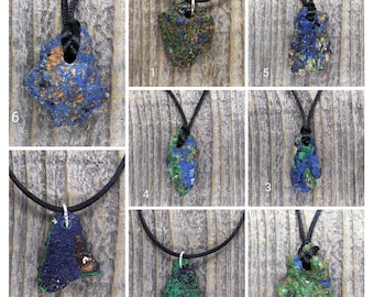 Puede incluir: Nueve collares con diferentes colgantes de piedra azul y verde. Los colgantes son todos de formas irregulares y tienen un aspecto natural y tosco. Los collares son todos de cordón negro.