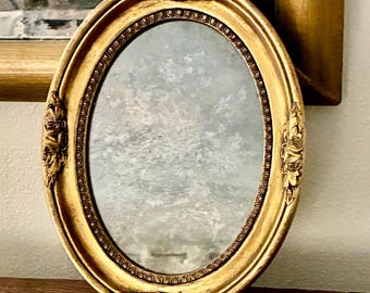 1968年製ヴィンテージオーバル型金メッキ壁掛け鏡 – ハリウッド・リージェンシー様式の金フレーム、スモーキーガラス、ロココ・ヴィクトリアン様式の装飾