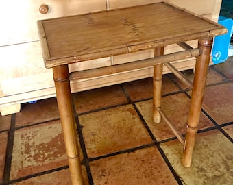 May include: A rectangular side table constructed from natural bamboo. The table features a flat, slatted top surface and four cylindrical bamboo legs connected by horizontal support bars on the sides, showcasing a light brown wood grain finish.
