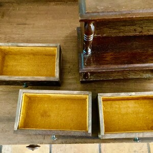 May include: A wooden jewelry box with four compartments. The box has a dark brown finish and each compartment is lined with a yellow fabric.