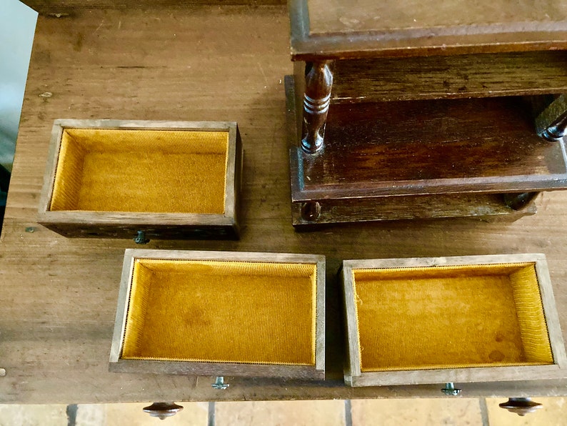 May include: A wooden jewelry box with four compartments. The box has a dark brown finish and each compartment is lined with a yellow fabric.