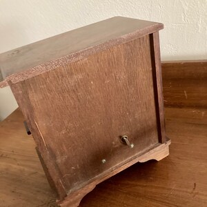 May include: A wooden music box with a winding key on the side. The box has a dark brown finish and a simple design.