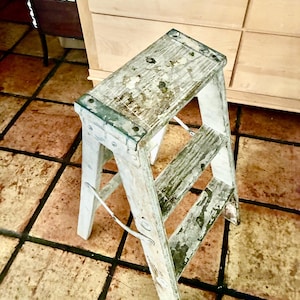 May include: A set of three ceramic mugs with a speckled, cream-colored glaze. Each mug features a different hand-painted floral design in shades of blue, green, and yellow. The mugs have a simple, rounded shape and a comfortable handle.