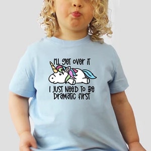 May include: Light blue t-shirt with a unicorn graphic and the text "I'll get over it I just need to be dramatic first".