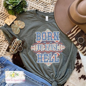 May include: A green t-shirt with a blue, red, and orange graphic design that says "Born to Raise Hell".