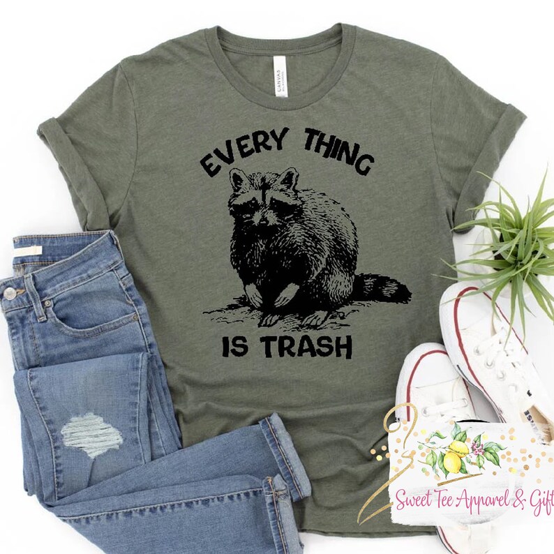 May include: A green t-shirt with a black raccoon graphic and the text "EVERY THING IS TRASH".